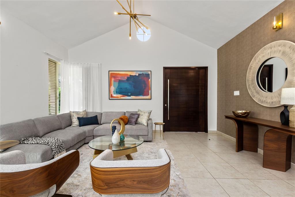 A modern living room features a vaulted ceiling, gray sectional sofa, and a wood console table — 418 CAMINO DEL SUSUA, DORADO, PR