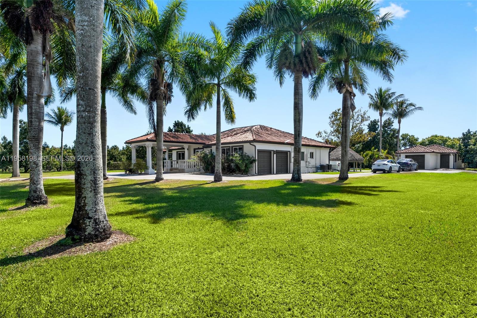 A single-story house with a tiled roof and palm trees sits on a grassy lawn — 16800 SW 190th St, Miami FL 33187, MIAMI, FL