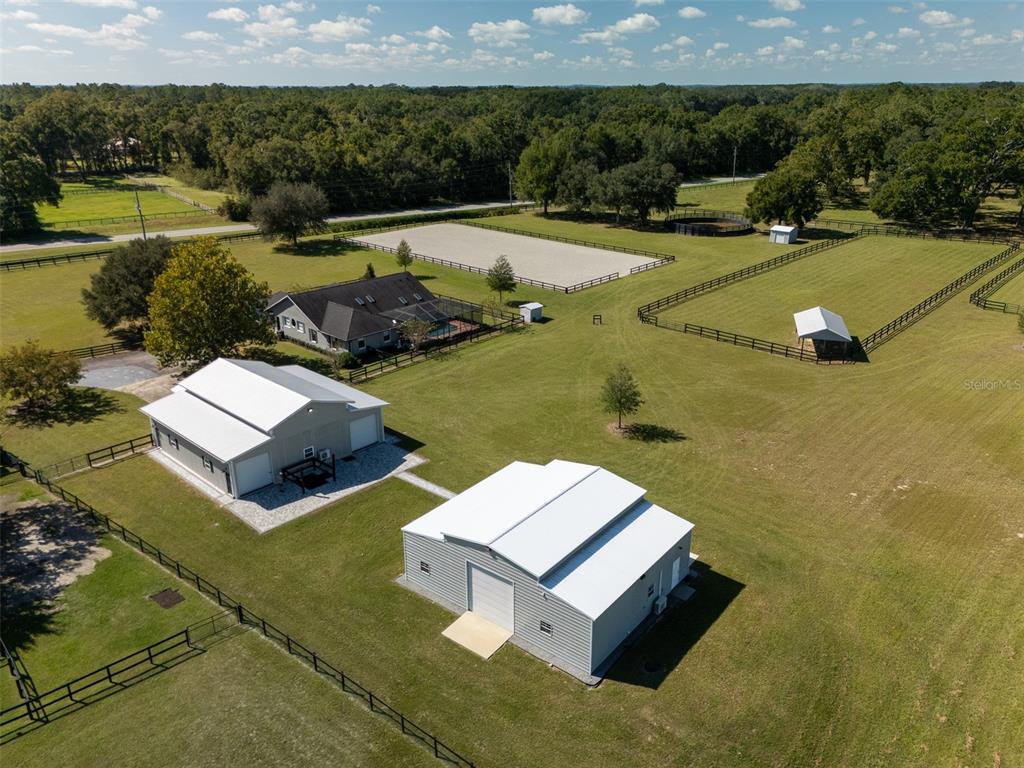 An aerial view shows a rural property with a house, two workshops, and fenced pastures — 15921 NW HIGHWAY 464B, MORRISTON, FL