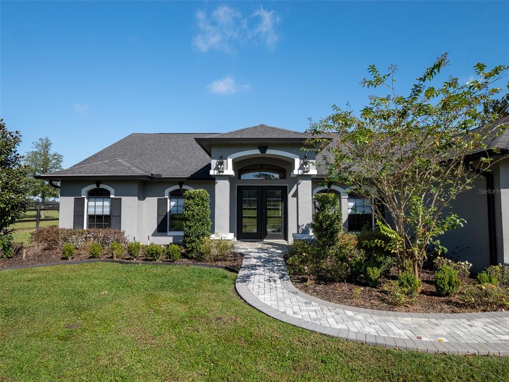 A single-story house with a gray exterior, a paved walkway, and a double front door — 15921 NW HIGHWAY 464B, MORRISTON, FL