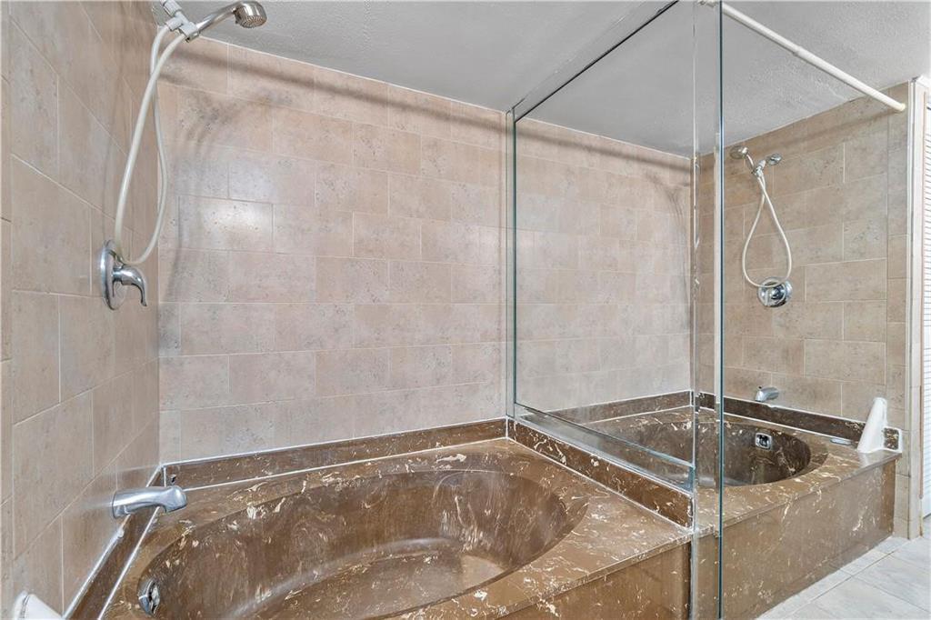 A bathroom features a large brown marble soaking tub and a separate glass-enclosed shower area — 1000 Parkview Drive # 507, Hallandale Beach FL 33009, HALLANDALE BEACH, FL