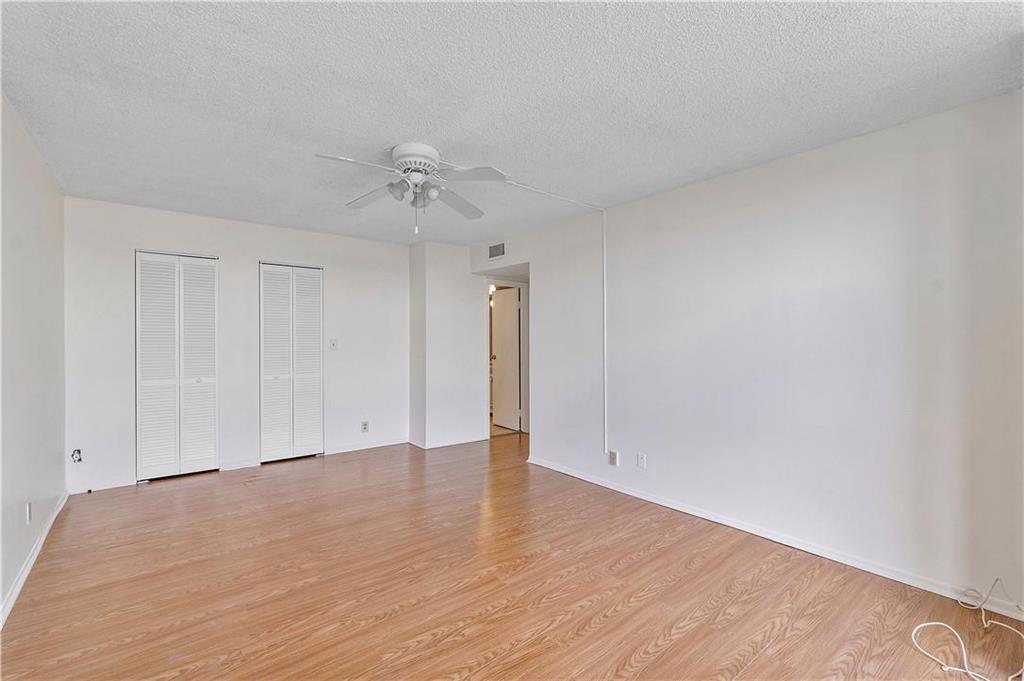 An empty bedroom features light wood-look flooring, white walls, a ceiling fan, and two closet doors — 1000 Parkview Drive # 507, Hallandale Beach FL 33009, HALLANDALE BEACH, FL