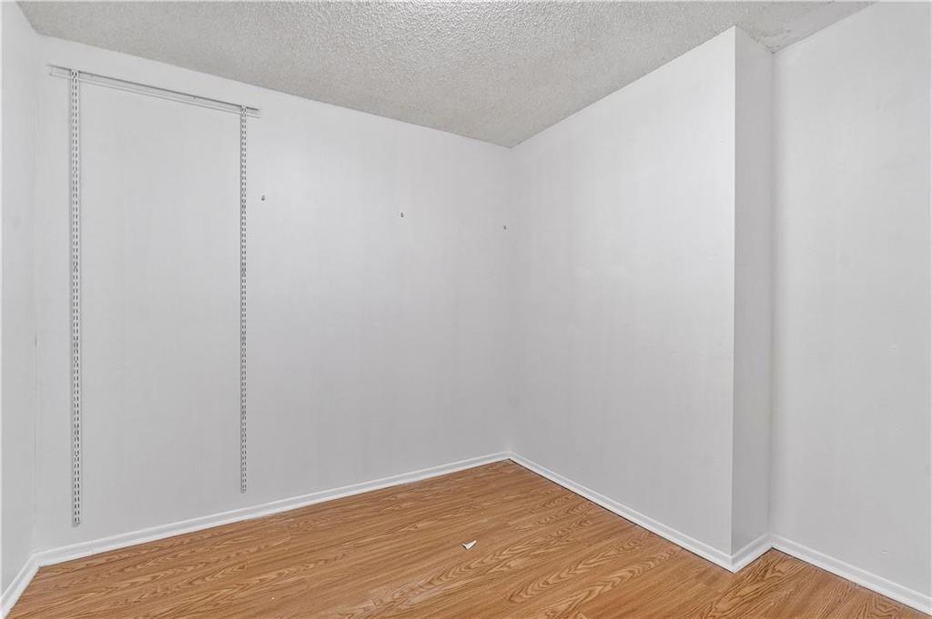 An empty room with white walls, wood-look flooring, and vertical wall-mounted shelving tracks — 1000 Parkview Drive # 507, Hallandale Beach FL 33009, HALLANDALE BEACH, FL