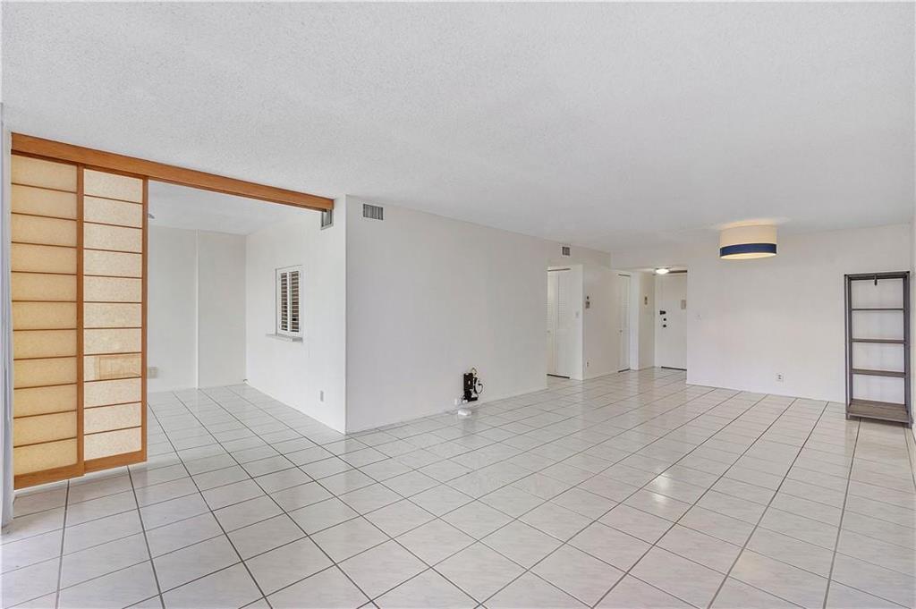 A spacious, white-tiled living area features a sliding shoji-style screen and a modern ceiling light — 1000 Parkview Drive # 507, Hallandale Beach FL 33009, HALLANDALE BEACH, FL