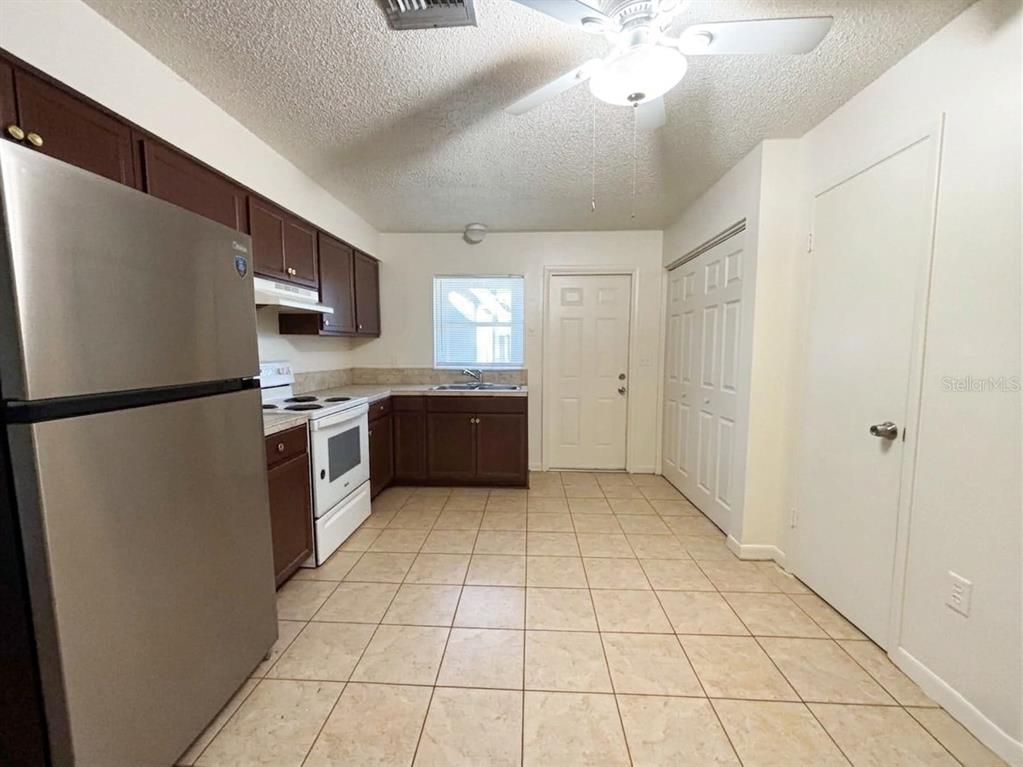 A kitchen features dark wood cabinets, stainless steel appliances, tile flooring, and a ceiling fan — 1236 JOSEPHINE STREET, LAKELAND, FL