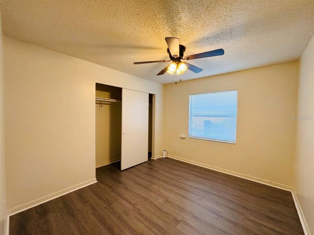 A bedroom with beige walls, wood-look flooring, a ceiling fan, and a sliding closet door — 1236 JOSEPHINE STREET, LAKELAND, FL