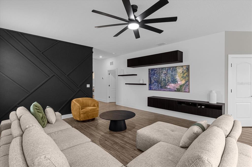 A living room features a black accent wall, a sectional sofa, and a ceiling fan — 7962 RUMNEY LANE, REUNION, FL