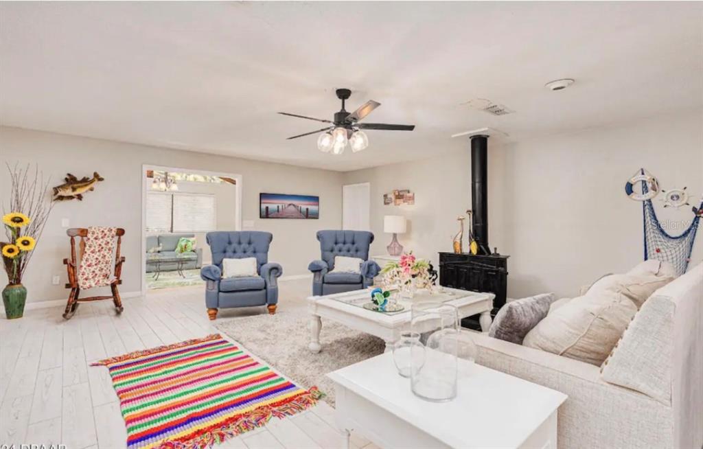 A living room features white wood-look floors, two blue armchairs, a sofa, and a fireplace — 400 PALM AVENUE, ORMOND BEACH, FL