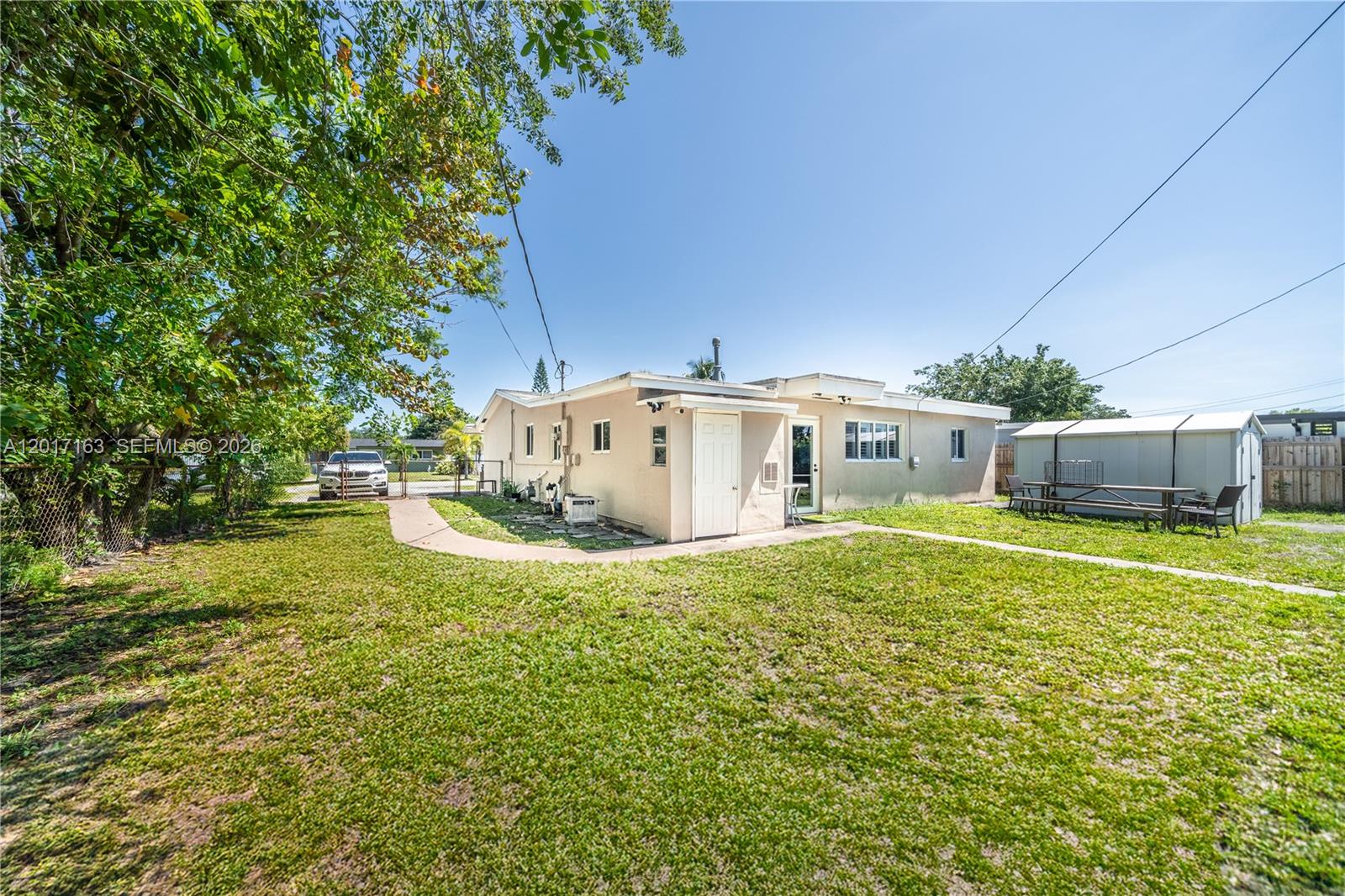 The exterior of a single-story house features a beige stucco facade and a grassy yard — 6472 Pierce St, Hollywood FL 33024, HOLLYWOOD, FL