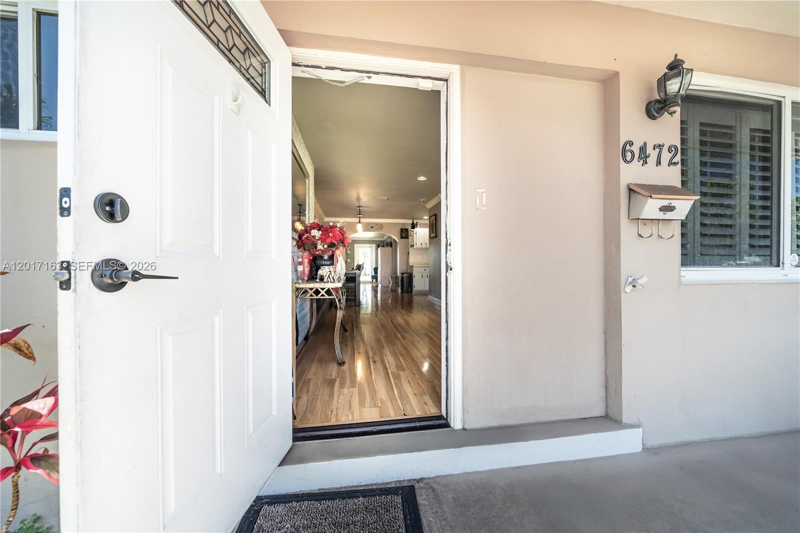 An open white front door reveals a view into a home with hardwood floors — 6472 Pierce St, Hollywood FL 33024, HOLLYWOOD, FL