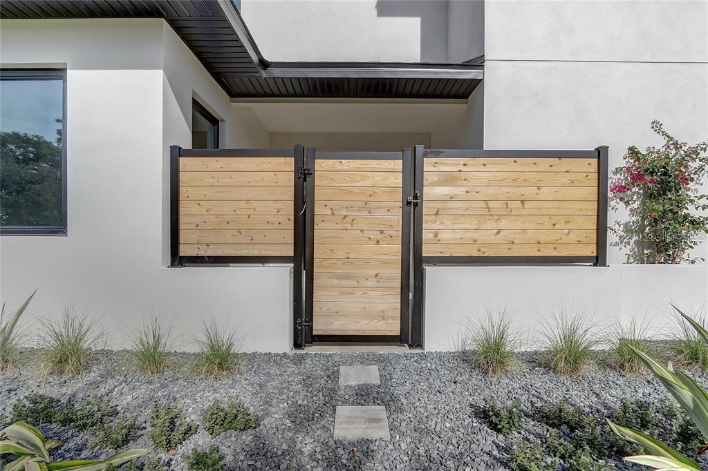 A modern home entrance features a wooden gate set within a black metal frame — 641 NORTHWOOD CIRCLE, WINTER PARK, FL