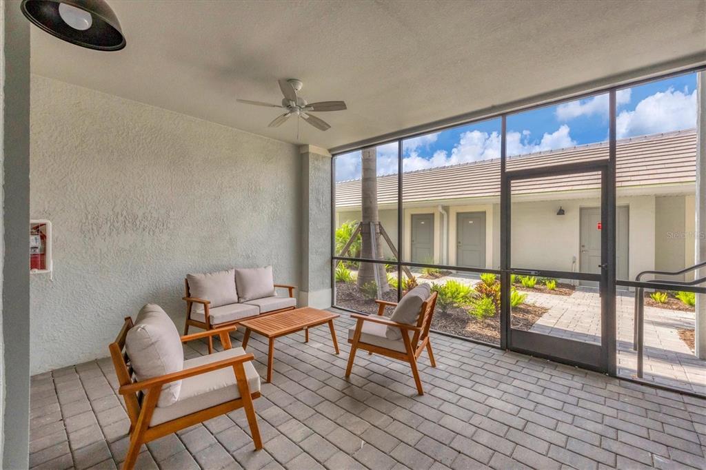 A screened-in patio features a paved floor, outdoor furniture, a ceiling fan, and exterior views — 12390 WELLEN GOLF STREET UNIT 106, VENICE, FL
