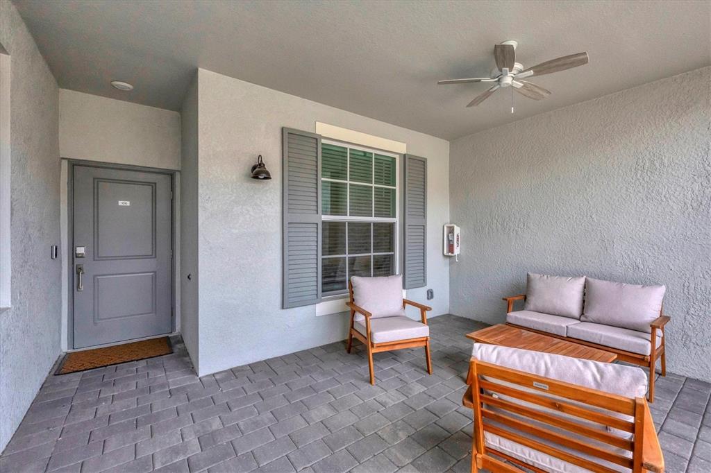 A covered patio features gray walls, a ceiling fan, and wooden patio furniture — 12390 WELLEN GOLF STREET UNIT 106, VENICE, FL