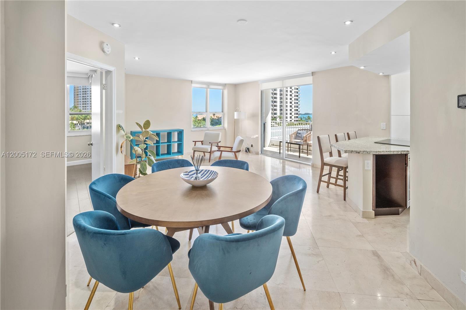 A dining area with a round table and blue chairs sits adjacent to a kitchen — 701 Brickell Key Blvd # 710, Miami FL 33131, MIAMI, FL