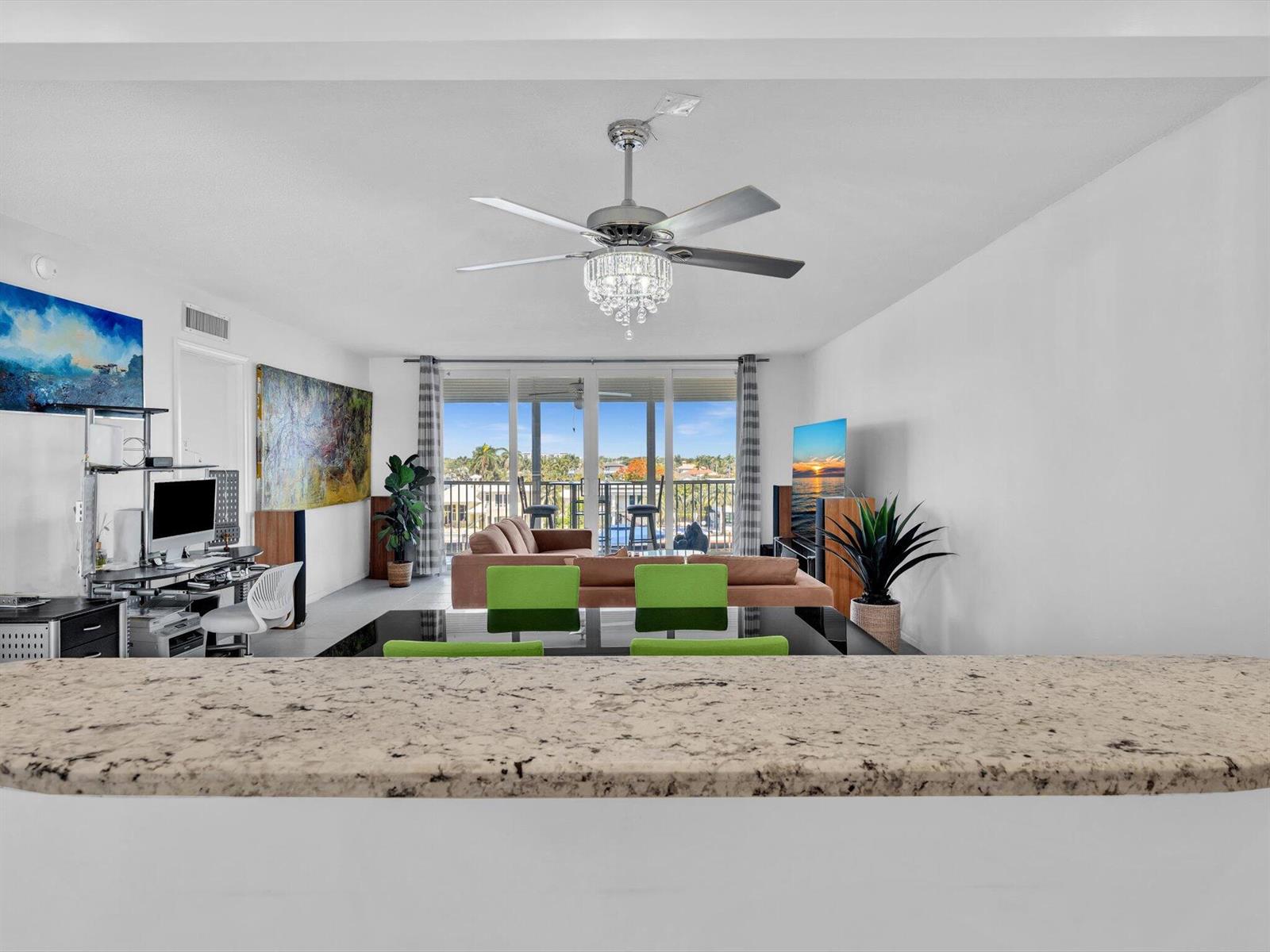 A living room with a ceiling fan, dining area, and balcony view through sliding doors — 303 N Riverside Drive # 503, Pompano Beach FL 33062, POMPANO BEACH, FL