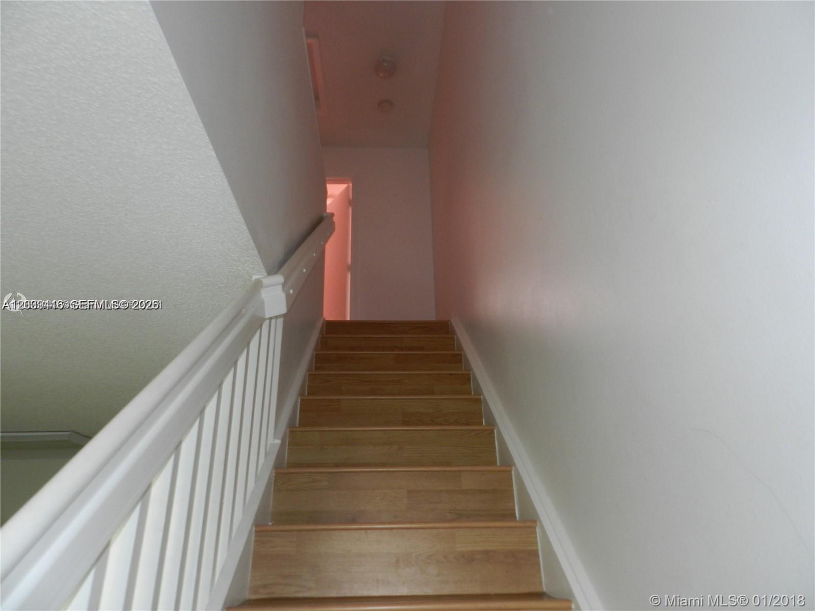 A wooden staircase with a white railing leads to a hallway with a doorway — 2167 Madeira Dr # 2167, Weston FL 33327, WESTON, FL