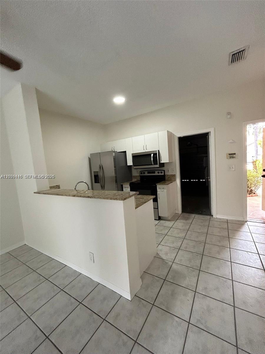 A kitchen features white cabinets, stainless steel appliances, granite countertops, and light tile flooring — 2167 Madeira Dr # 2167, Weston FL 33327, WESTON, FL