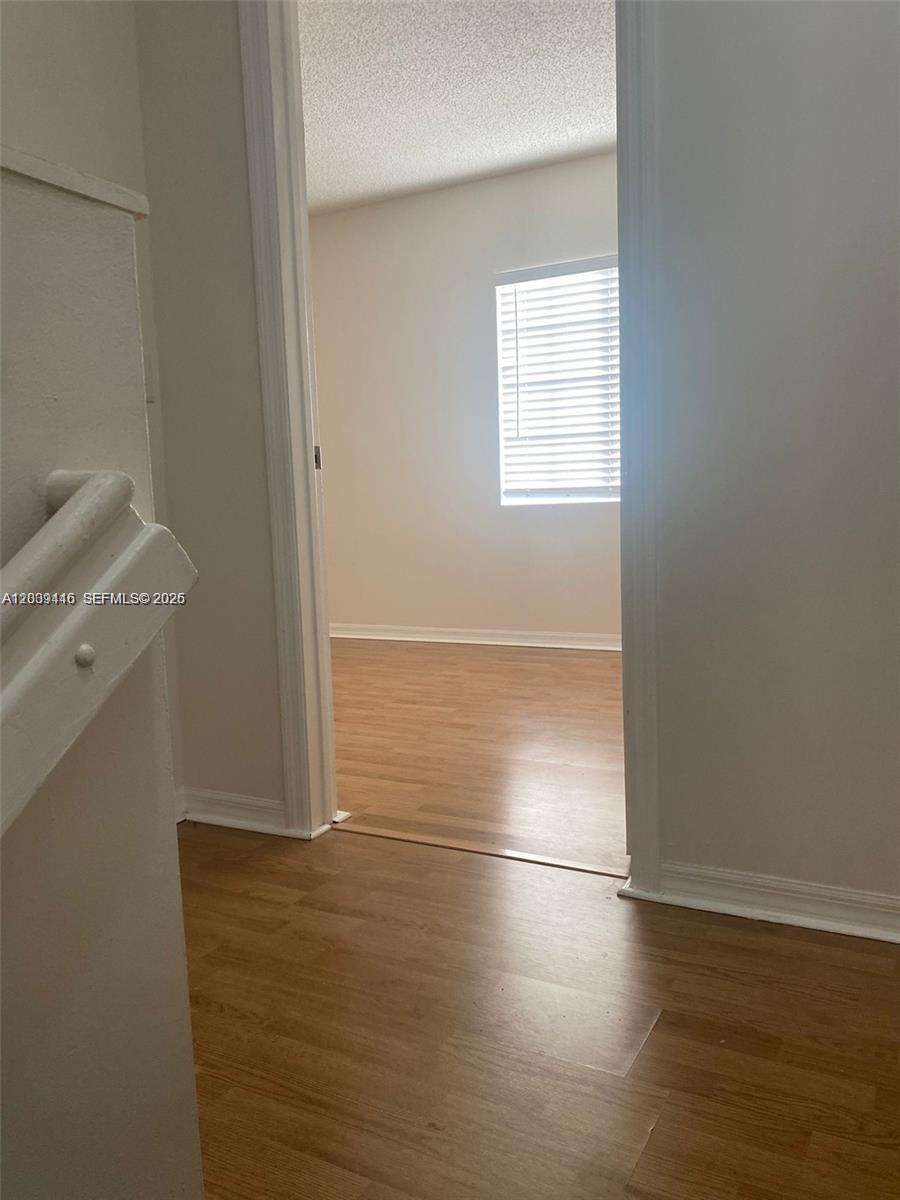 A view from a hallway looking into a bedroom with light wood-look flooring — 2167 Madeira Dr # 2167, Weston FL 33327, WESTON, FL