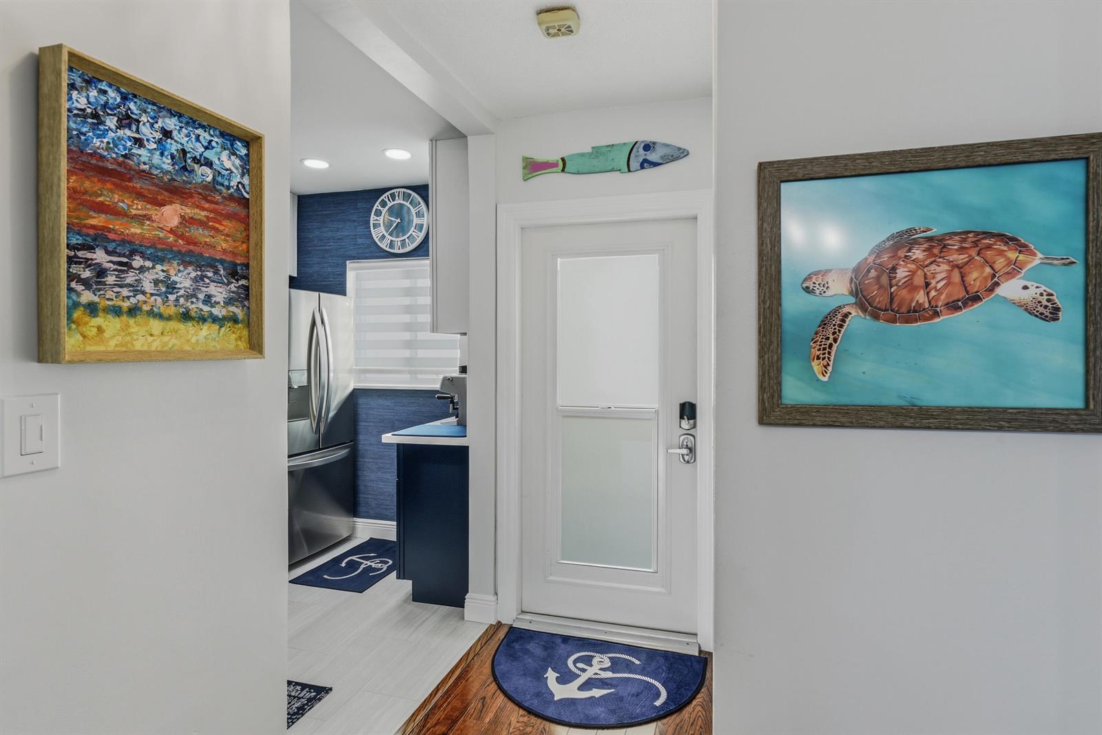 A hallway leads into a kitchen with blue wallpaper, stainless appliances, and nautical-themed wall art — 6530 N Ocean Boulevard # 3070, Ocean Ridge FL 33435, OCEAN RIDGE, FL