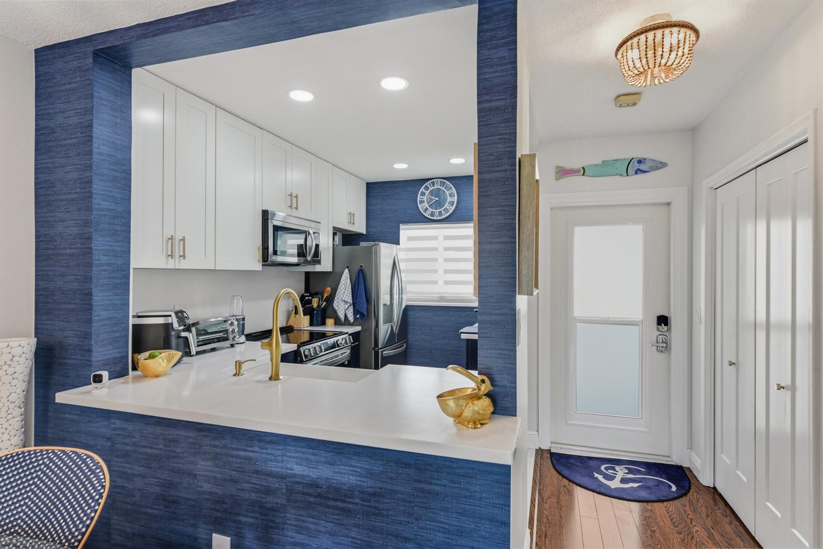 A kitchen with white cabinets, blue textured walls, and a gold faucet overlooks a hallway — 6530 N Ocean Boulevard # 3070, Ocean Ridge FL 33435, OCEAN RIDGE, FL