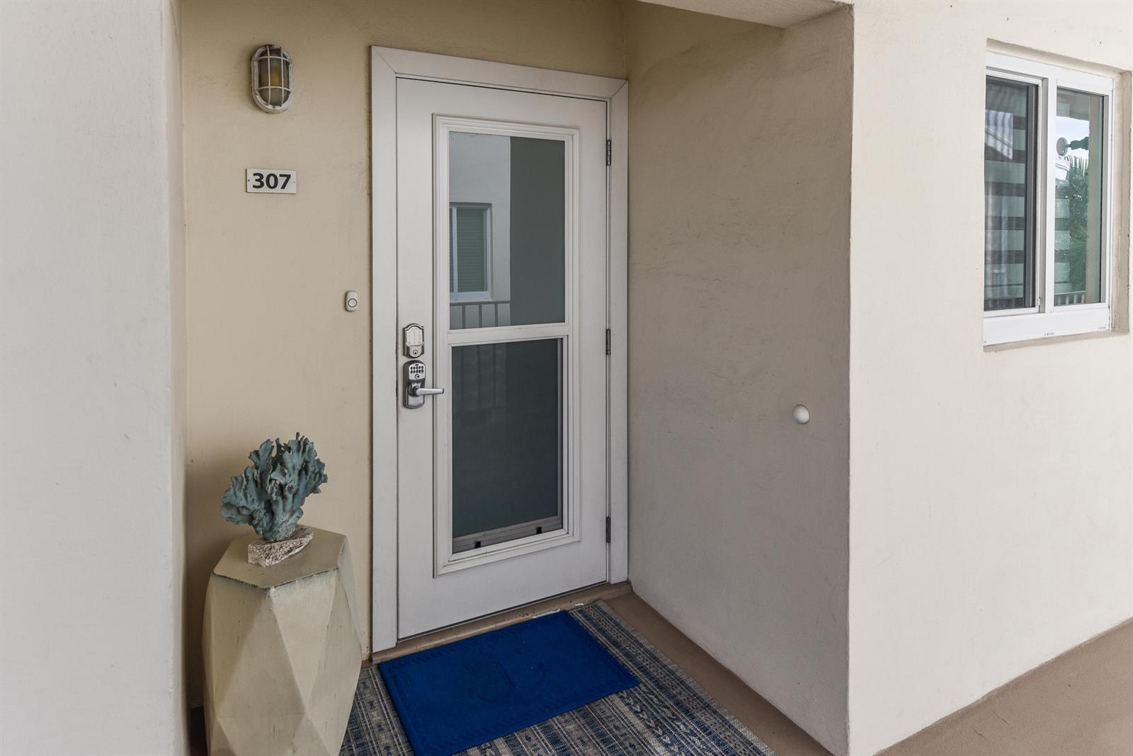 A white door with a glass panel and a blue mat sits beside a window — 6530 N Ocean Boulevard # 3070, Ocean Ridge FL 33435, OCEAN RIDGE, FL