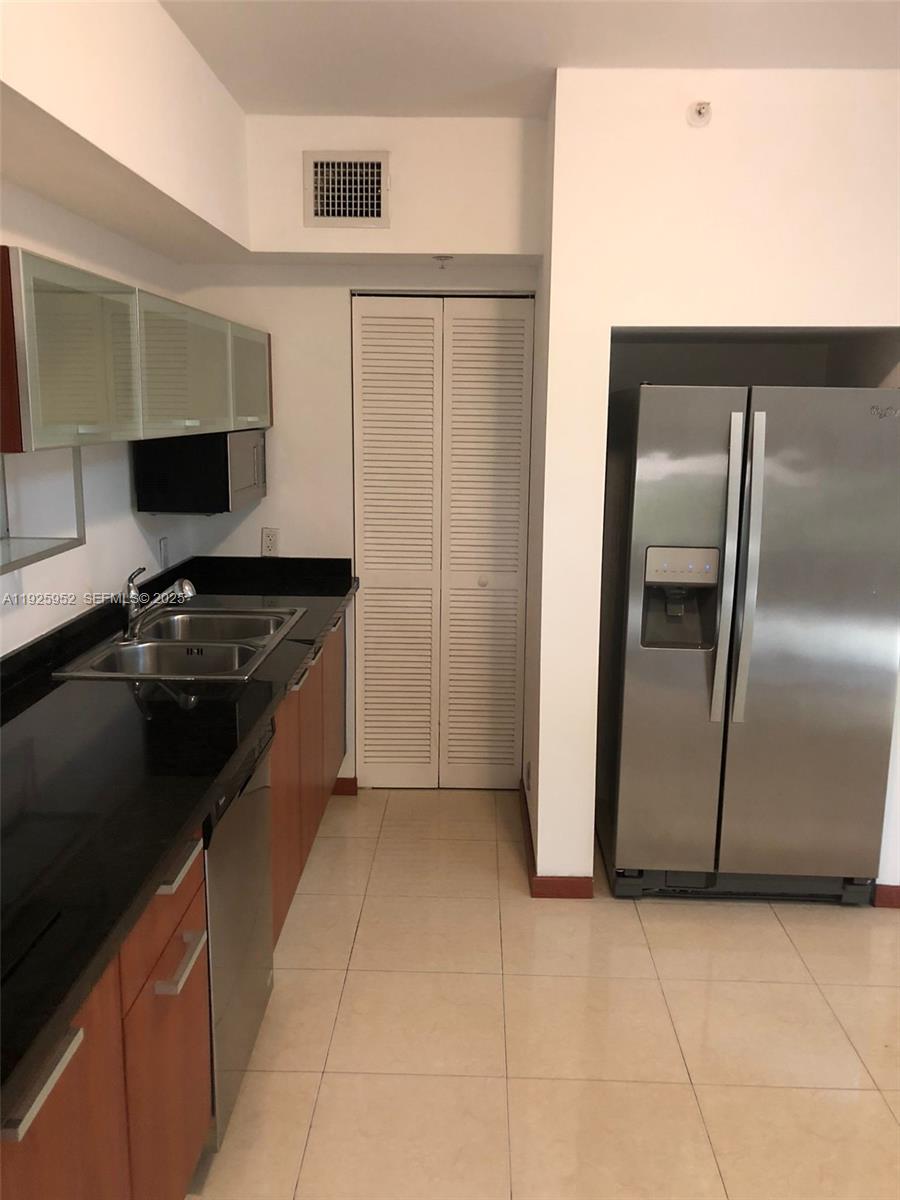A kitchen features stainless steel appliances, dark countertops, wood cabinets, and light-colored floor tiles — 1650 Brickell Ave # 111, Miami FL 33129, MIAMI, FL