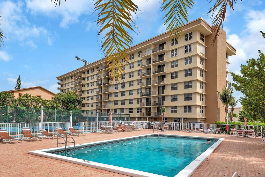 A swimming pool sits in front of a multi-story apartment building with balconies — 1009 N Ocean Boulevard N # 503, Pompano Beach FL 33062, POMPANO BEACH, FL