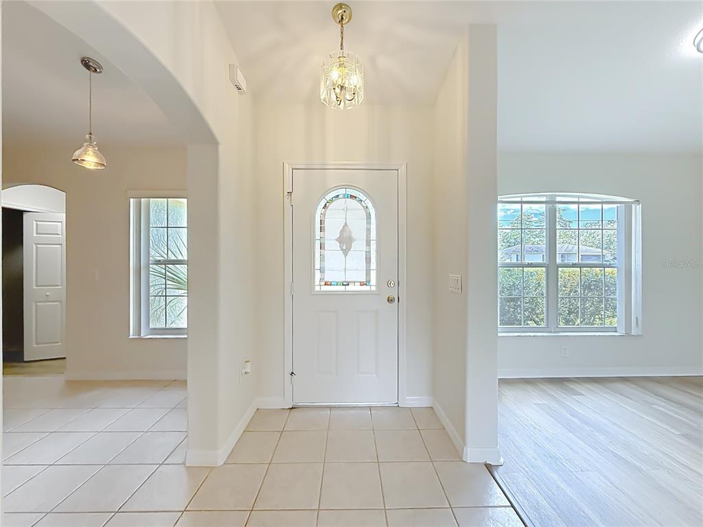 An entryway with a white front door, tiled floor, and a crystal chandelier — 626 MARION OAKS LANE, OCALA, FL