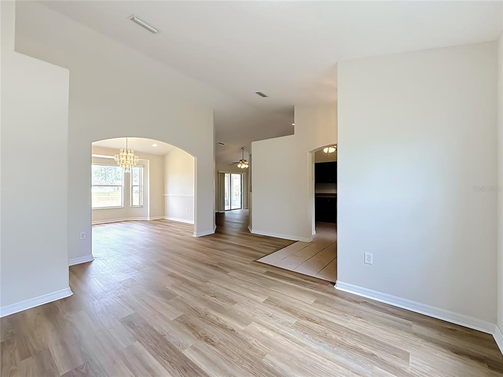 An interior view of a living area with light wood flooring and arched doorways — 626 MARION OAKS LANE, OCALA, FL