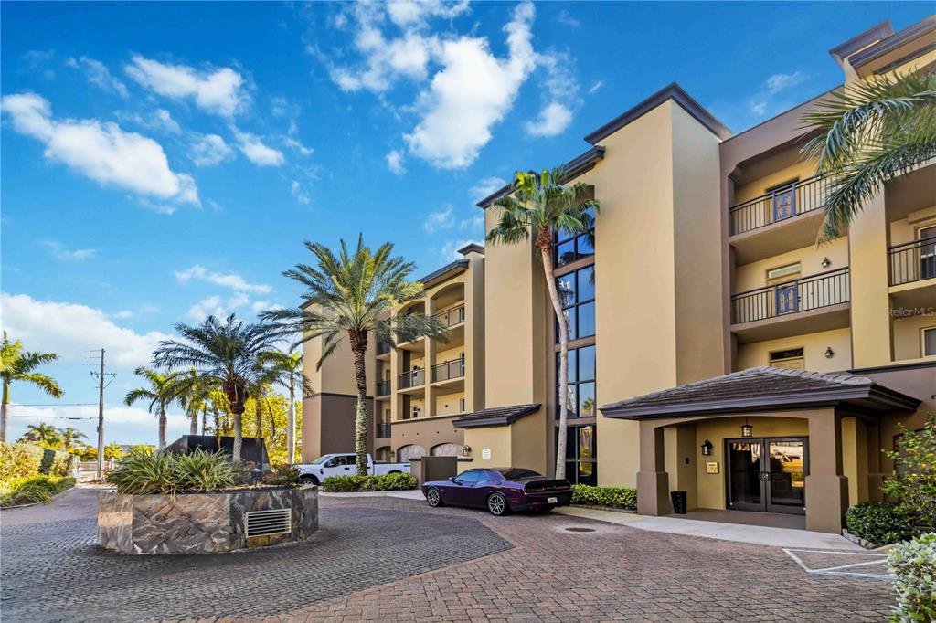 A multi-story apartment building with a paved driveway, palm trees, and a purple car parked outside — 4125 W END ROAD UNIT 306, COCOA BEACH, FL