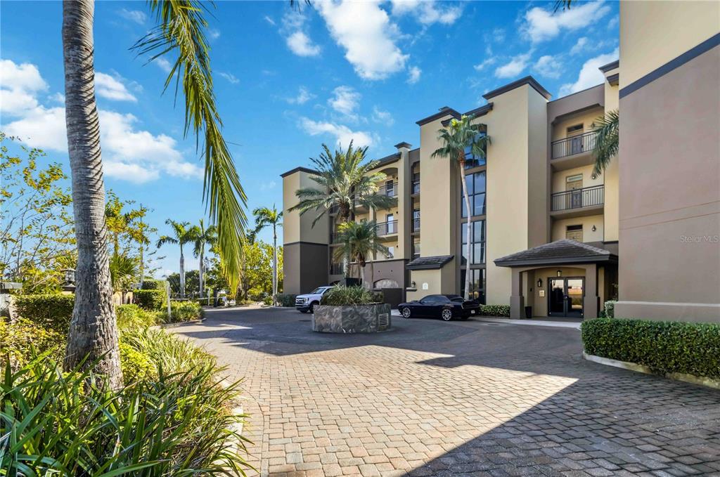 A multi-story apartment building exterior with a paved driveway, palm trees, and a covered entrance — 4125 W END ROAD UNIT 306, COCOA BEACH, FL