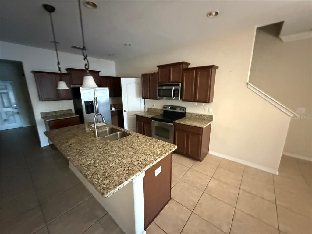 A kitchen features dark wood cabinets, granite countertops, a center island, and stainless steel appliances — 1511 HARBOUR BLUE STREET, RUSKIN, FL