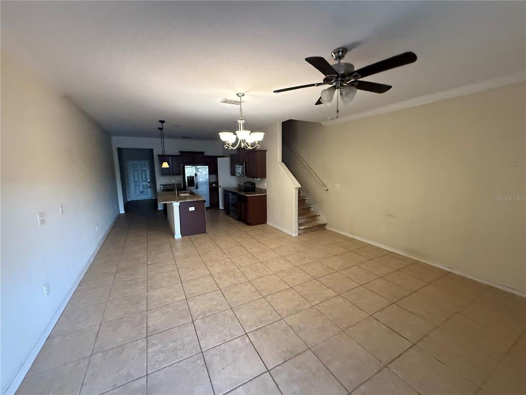 An open-concept living area features tile flooring, a kitchen with dark cabinetry, and a staircase — 1511 HARBOUR BLUE STREET, RUSKIN, FL