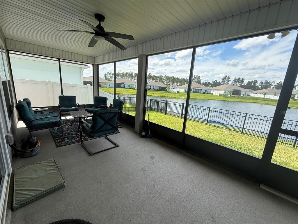 A screened-in patio features a ceiling fan, outdoor furniture, and a view of a pond — 59 HULETT WOODS ROAD, PALM COAST, FL