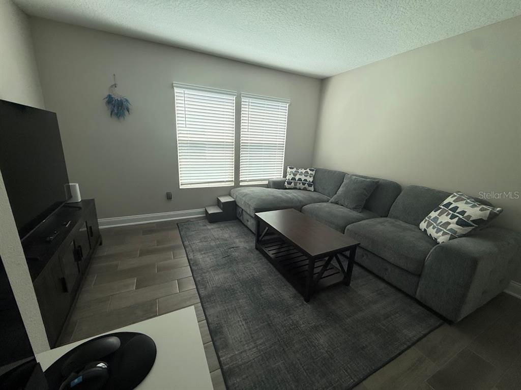 A living room features a gray sectional sofa, a coffee table, and a television console — 59 HULETT WOODS ROAD, PALM COAST, FL
