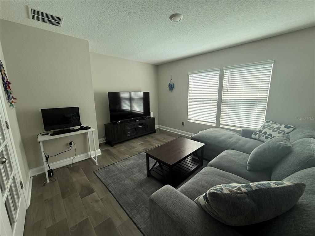 A living room features a gray sectional sofa, a coffee table, and a television console — 59 HULETT WOODS ROAD, PALM COAST, FL
