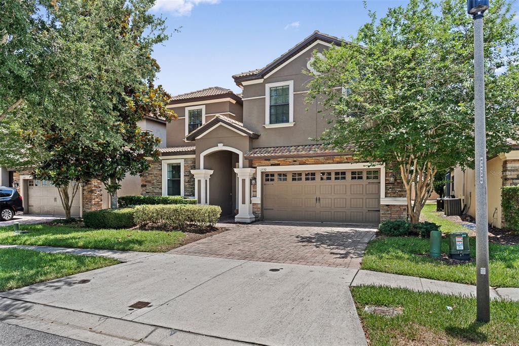 A two-story suburban house with a stone facade, a paved driveway, and a two-car garage — 1530 MOON VALLEY DRIVE, DAVENPORT, FL