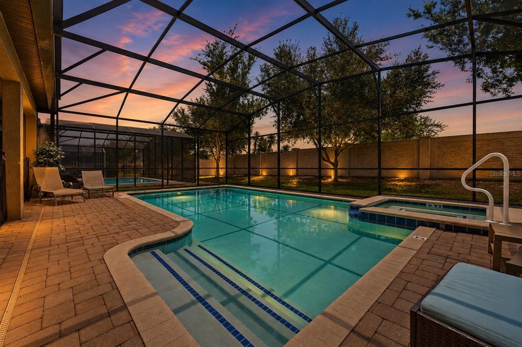 A screened-in swimming pool and spa with a brick paver deck at sunset — 1530 MOON VALLEY DRIVE, DAVENPORT, FL