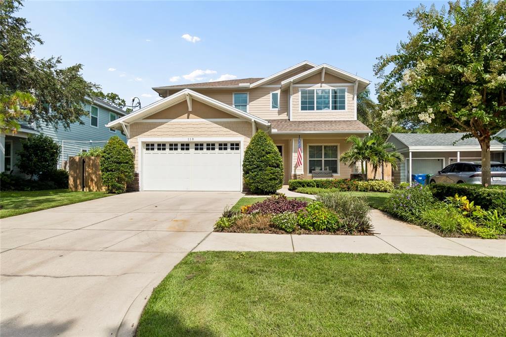 A two-story suburban house with a tan exterior, a two-car garage, and a landscaped yard — 110 S BEVERLY AVENUE, TAMPA, FL