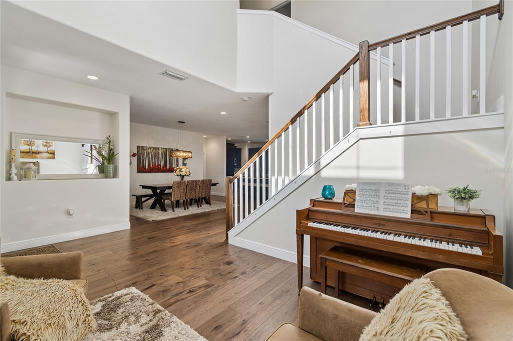 A living area features a wooden staircase, a piano, and a view into the dining room — 110 S BEVERLY AVENUE, TAMPA, FL