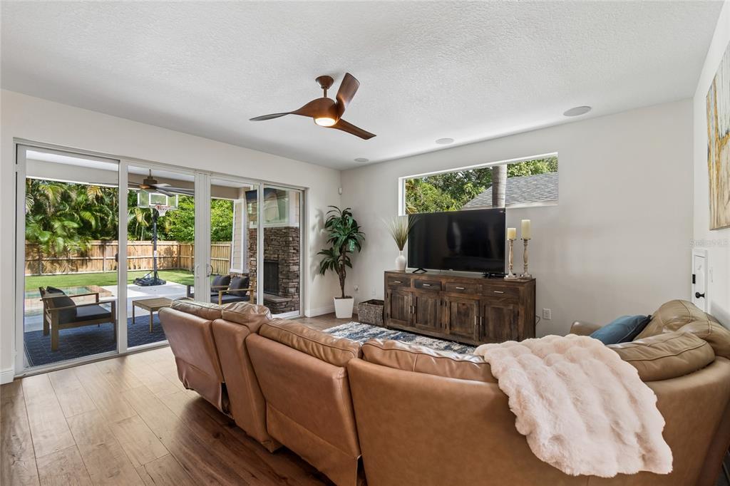 A living room features a leather sectional, wooden media console, ceiling fan, and sliding glass doors — 110 S BEVERLY AVENUE, TAMPA, FL