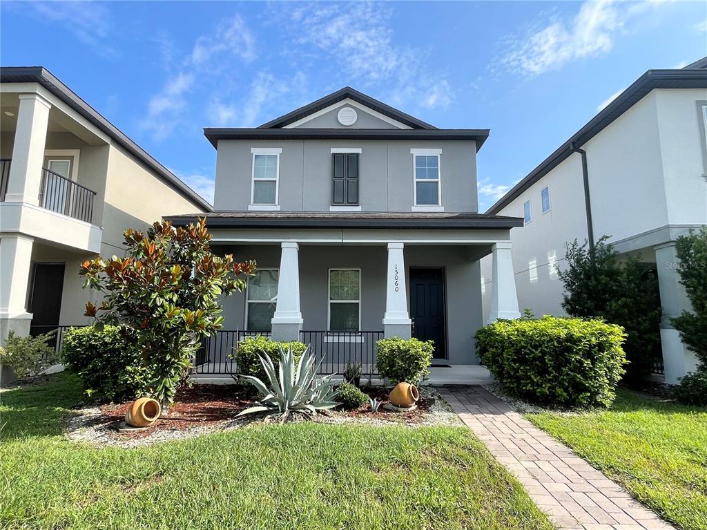 A two-story gray house features a front porch, white columns, and a paved walkway — 15060 WILLOW ARBOR CIRCLE, ORLANDO, FL