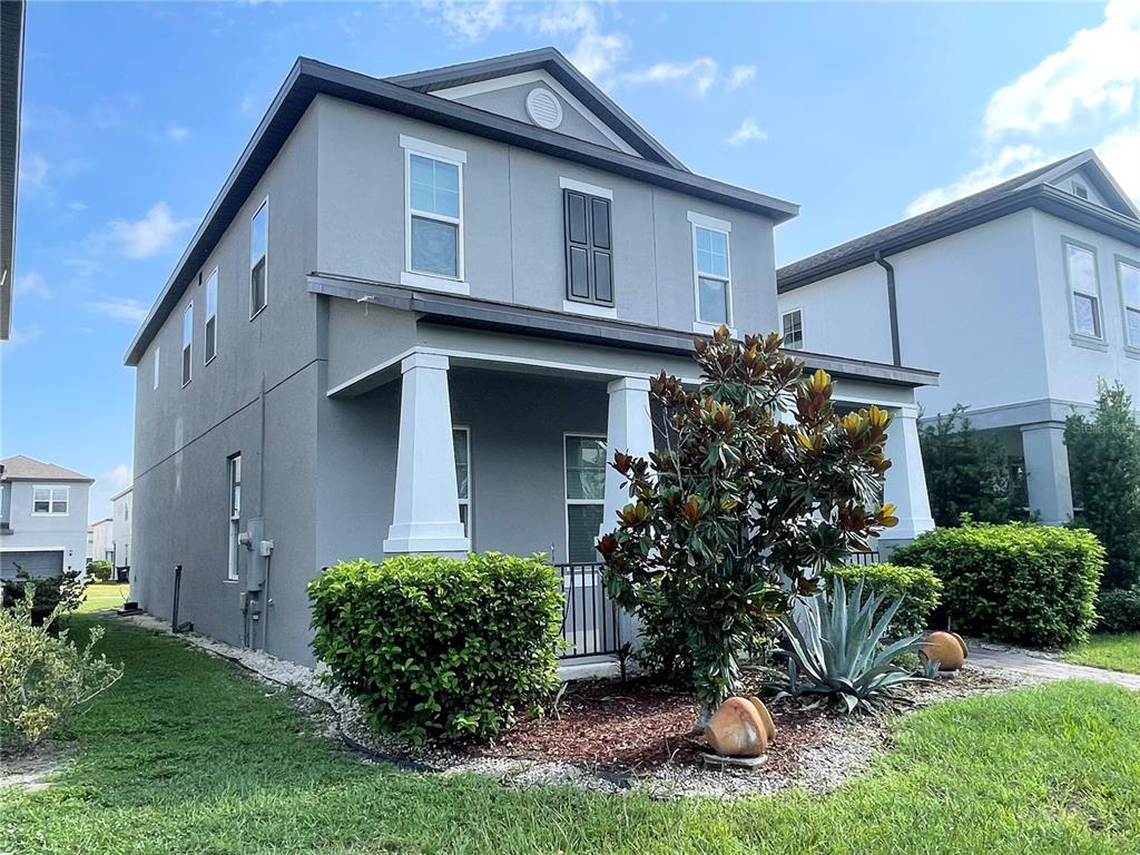 A two-story gray house with a front porch, white columns, and landscaped front yard — 15060 WILLOW ARBOR CIRCLE, ORLANDO, FL