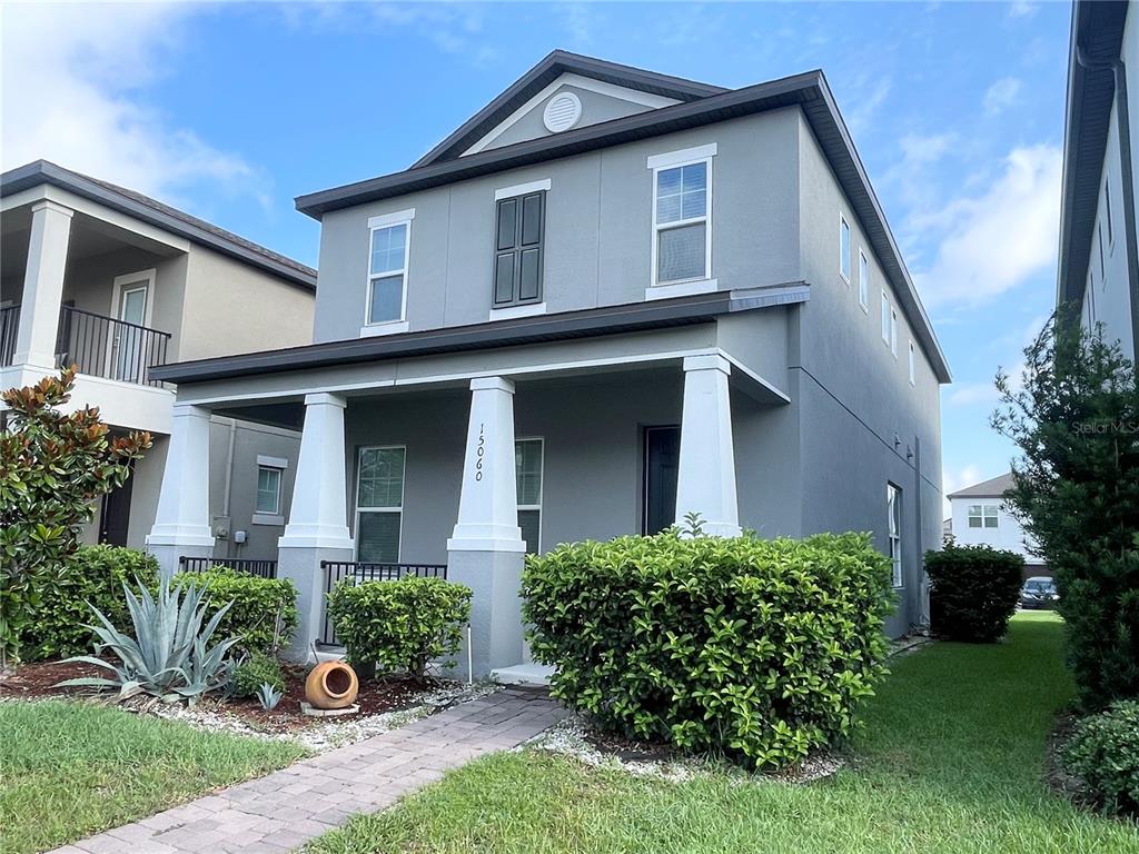 A two-story gray house features a covered front porch with white columns and landscaping — 15060 WILLOW ARBOR CIRCLE, ORLANDO, FL