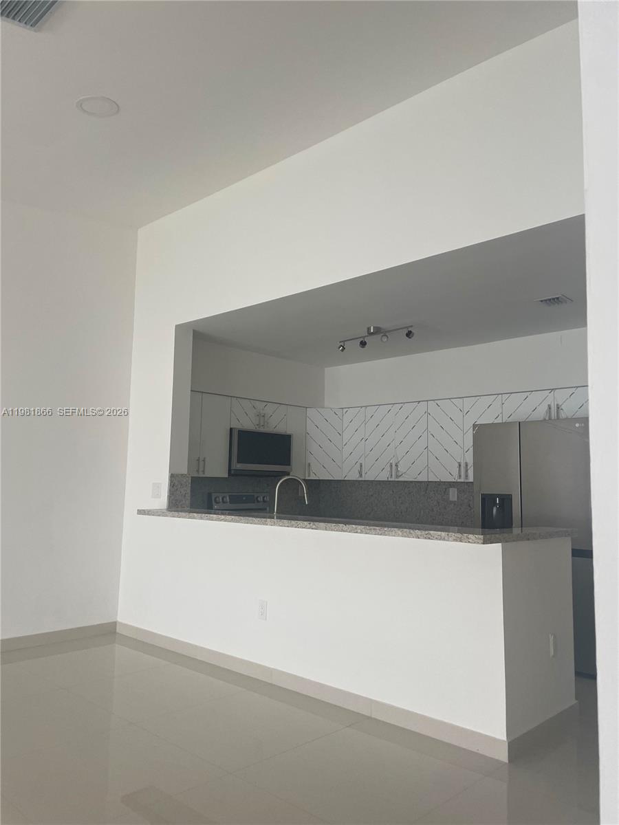 This kitchen features white cabinets with a chevron pattern, granite countertops, and stainless appliances — 14728 Balgowan Rd, Miami Lakes FL 33016, MIAMI LAKES, FL