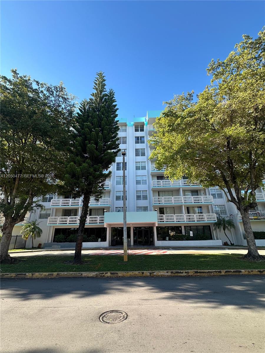 A multi-story apartment building features white balconies and a central entrance under a blue canopy — 15600 NW 7th Ave # 501, Miami FL 33169, MIAMI, FL