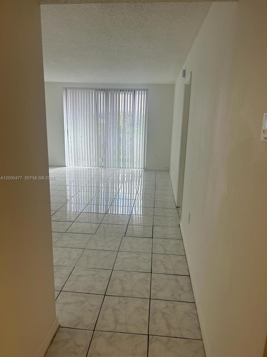 A bright room features white tiled floors and a large sliding glass door with blinds — 15600 NW 7th Ave # 501, Miami FL 33169, MIAMI, FL