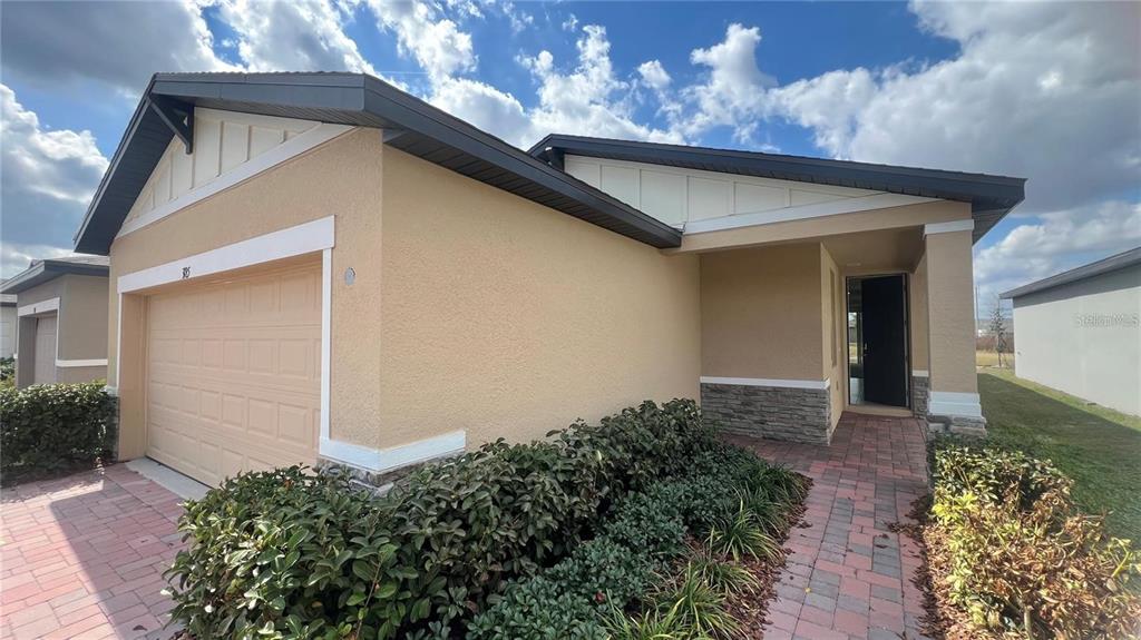 A single-story house with a tan stucco exterior, a two-car garage, and a brick walkway — 3185 VICEROY COURT, KISSIMMEE, FL