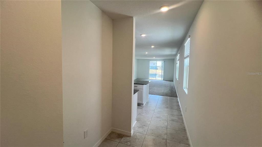 A tiled hallway leads to a kitchen and a carpeted living area with sliding doors — 3185 VICEROY COURT, KISSIMMEE, FL