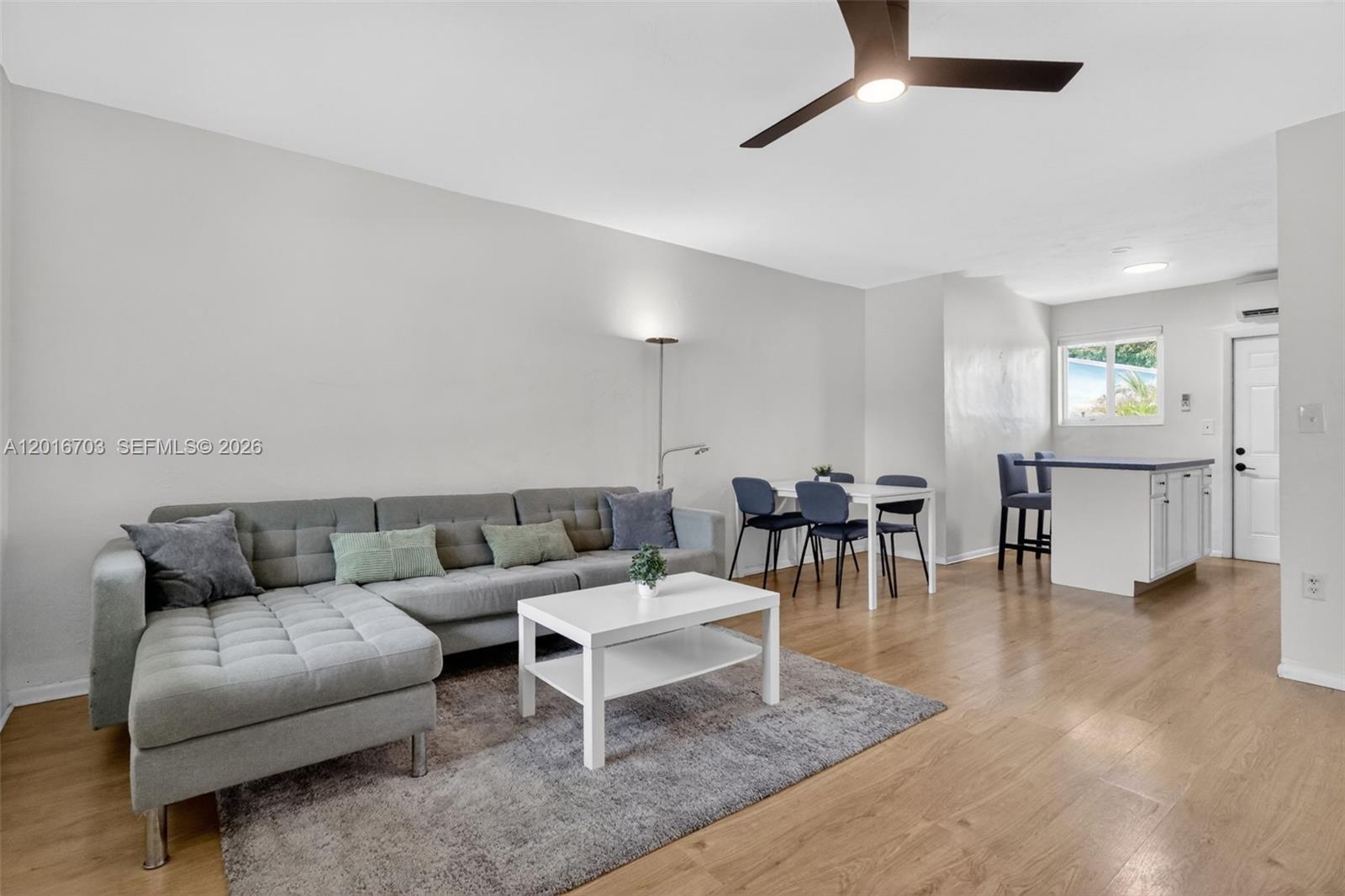 A living room features a grey sectional sofa, a white coffee table, and a dining area — 1003 NE 110th St # 1003, Biscayne Park FL 33161, BISCAYNE PARK, FL